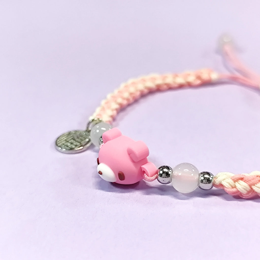 Hand - braided bracelet with a pink bear charm, beads, and a silver pendant. Cute and delicate accessory.