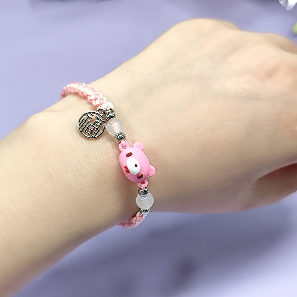 Hand - braided bracelet with a pink bear charm, beads, and a silver pendant. Cute and delicate accessory.
