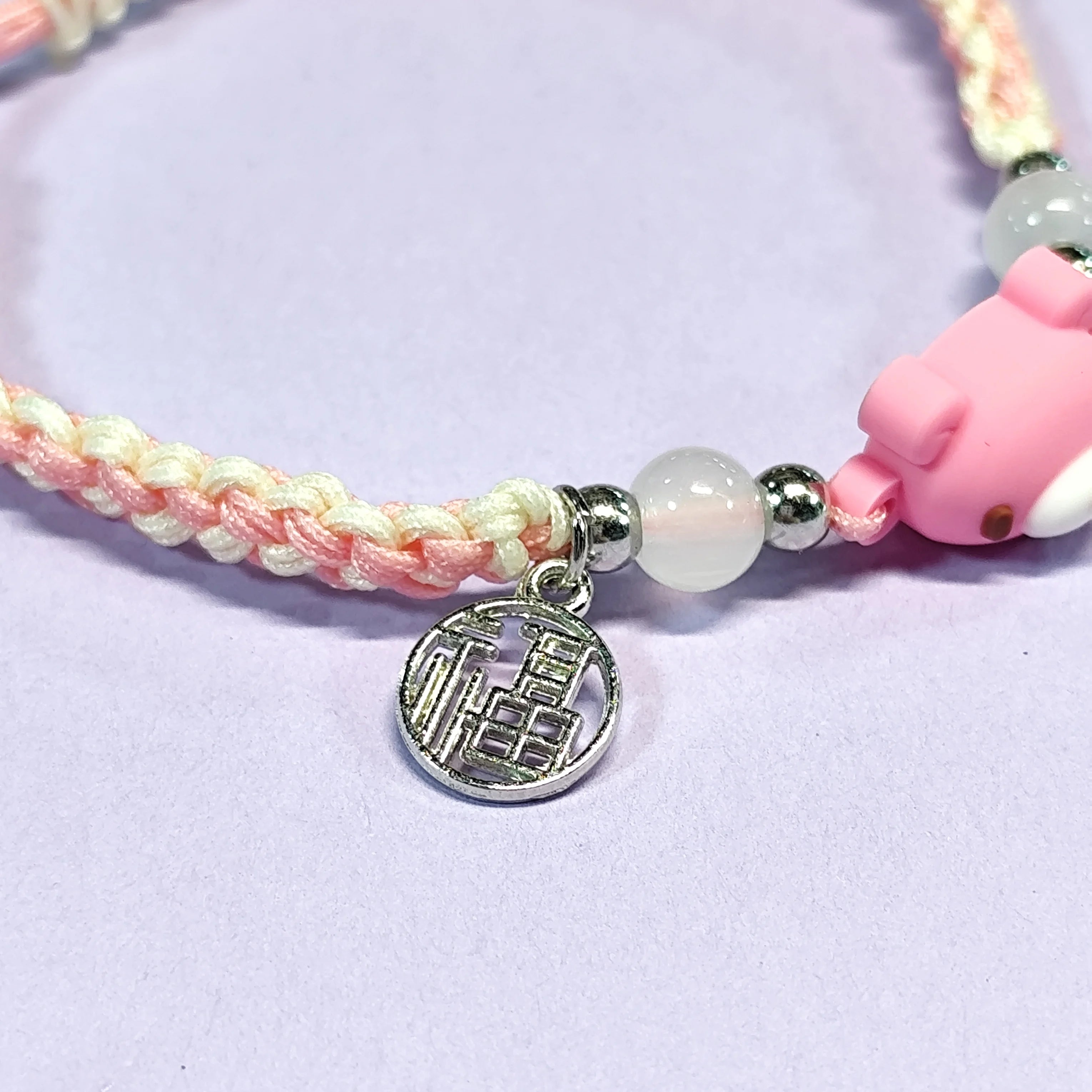 Hand - braided bracelet with a pink bear charm, beads, and a silver pendant. Cute and delicate accessory.